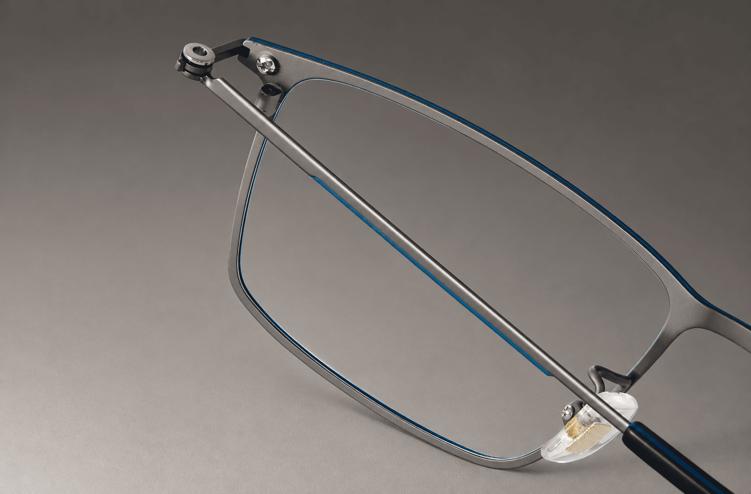 S-L7021 folded temple crossing the inside of the blue and gunmetal-tone titanium frame.