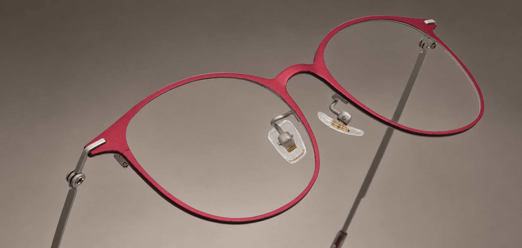 S-L7026 angled close-up of the crimson titanium front, curved bridge and silver-tone hinge connections.