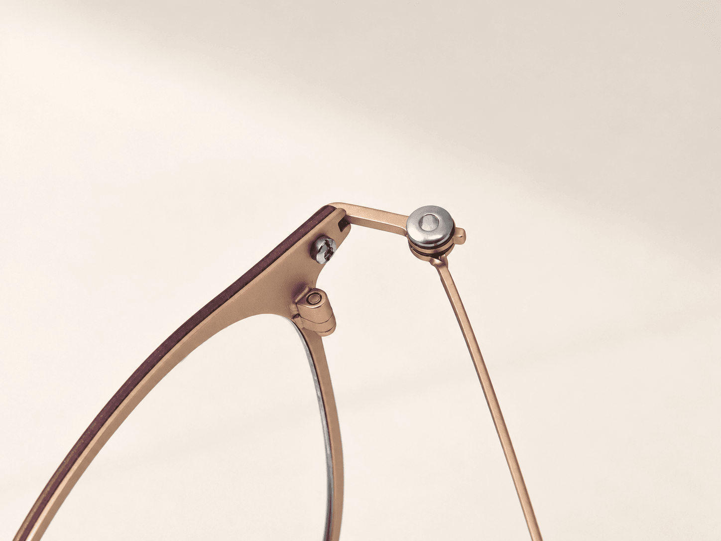 Opposite inner hinge and screw details on the plum and rose-gold-tone optical frame.