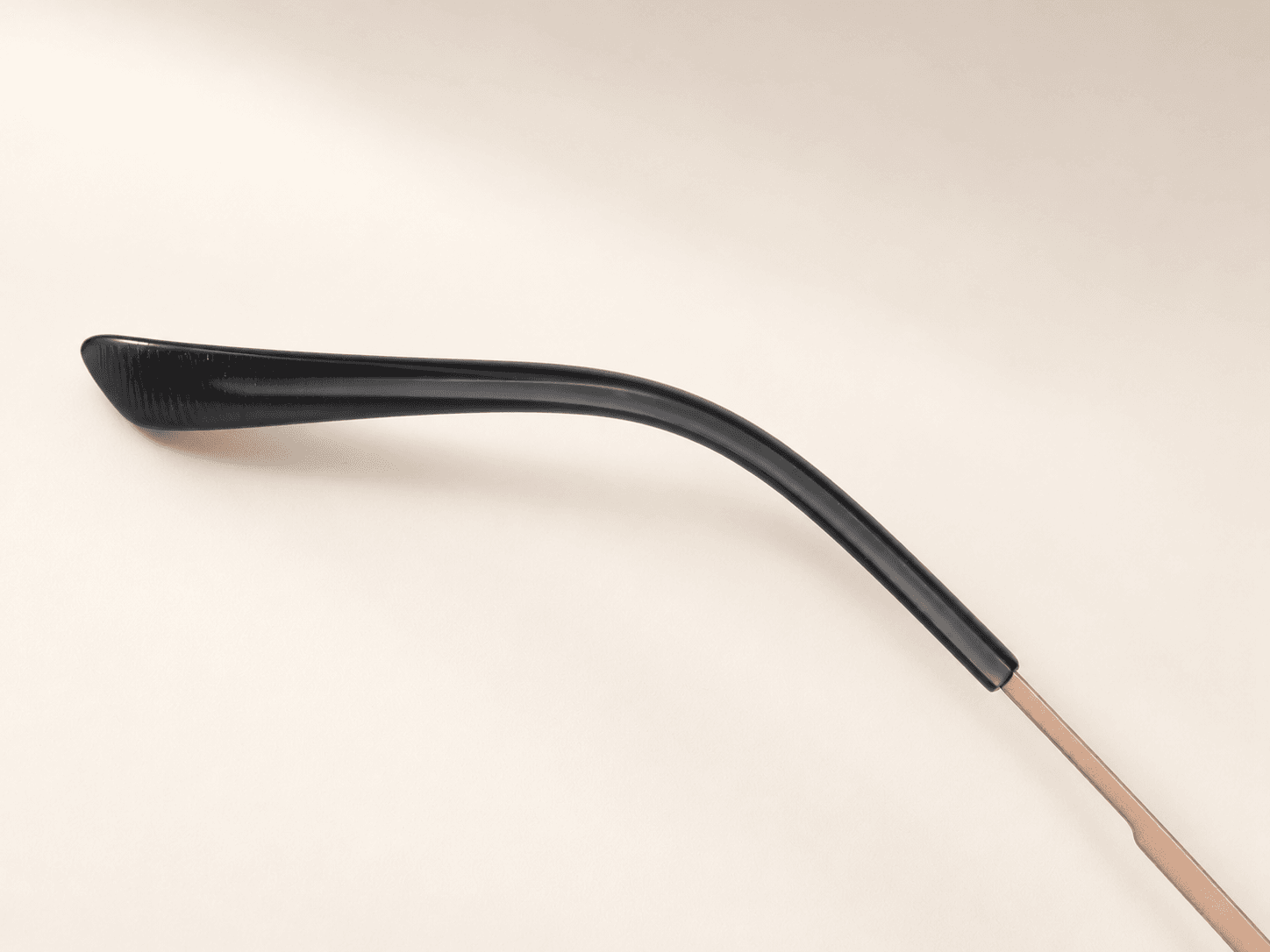 Black curved temple tip and slender rose-gold-tone metal temple.