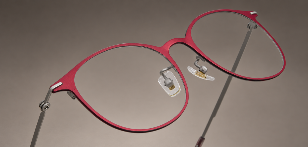 S-L7026 angled close-up of the crimson titanium front, curved bridge and silver-tone hinge connections.